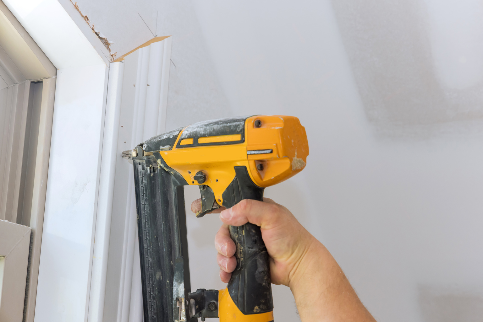 In our new home, a carpenter uses a brad nail gun to nail th